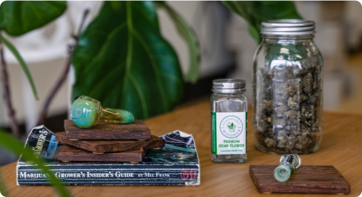 Hemp products and a pipe sitting on a table with plants in the background